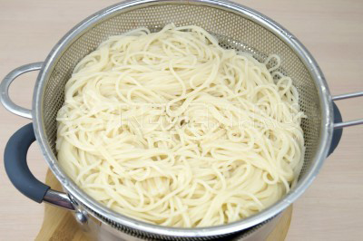 Откинуть спагетти на дуршлаг и дать воде полностью стечь.