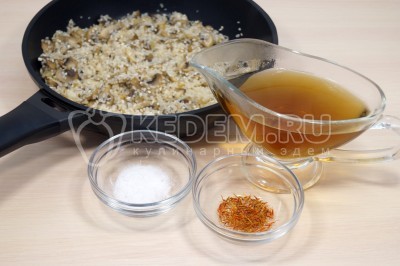 Добавить в сковороду часть грибного бульона, 1/2 чайной ложки соли и 1 щепотку шафрана.