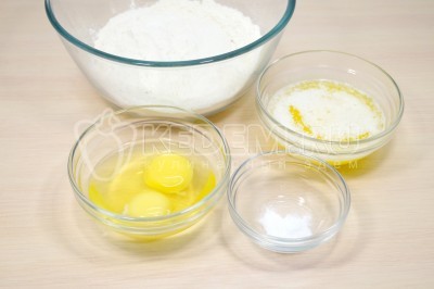 Добавить в миску с мукой 2 яйца, 100 грамм растопленного сливочного масла и 1 щепотку ванилина.
