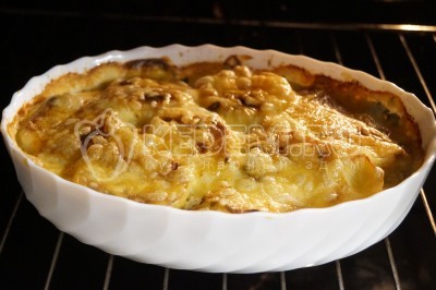 Запекать картофель с луком и сыром в духовке еще 10-12 минут.