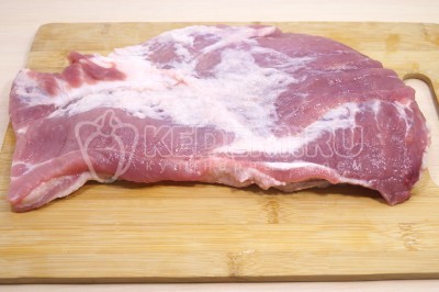 Чтобы приготовить мясной рулет с чесноком на Новый год нужно 1 кг свиной лопатки очистить от жилок, разрезать в пласт.