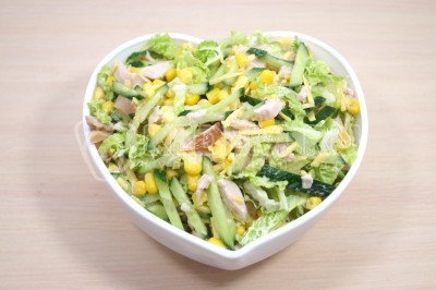 Выложить салат с копченым куриным филе, пекинской капустой, свежим огурцом, сыром и консервированной кукурузой в салатницу.