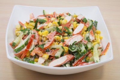 Перемещать салат с крабовыми палочками, кукурузой, огурцом и болгарским перцем и выложить в салатник.