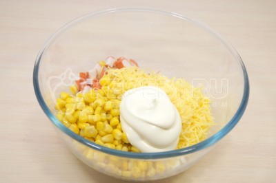 Добавить в миску с крабовыми палочками, сыром и кукурузой 2 столовые ложки майонеза и перемешать.