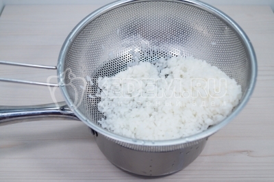 Откинуть отварной рис на сито и промыть.