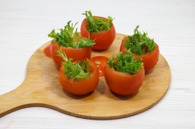 Наполнить помидоры небольшими листьями салата.
