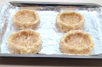 Разделить фарш на 4 части и сформировать гнезда на противне застеленном фольгой.