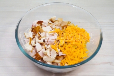 В миску добавить нарезанное куриное филе и тертый сыр.