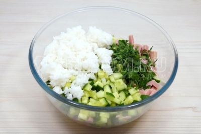 Добавить в салат отварной рис и мелко нарубленную зелень петрушки.