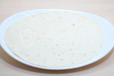 Чтобы приготовить рулетики из лаваша с красной икрой, нужно на лист круглого лаваша развернуть на большой тарелке или разделочной доске.