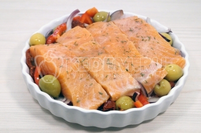 В форму для запекания выложить овощную подушку. Сверху выложить кусочки рыбы.