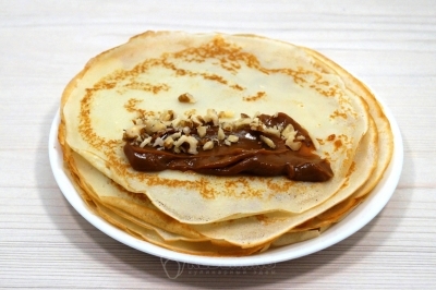 На блин выложить ложку вареной сгущенки. Добавить орехи.