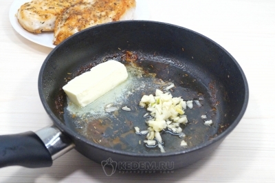 Курицу убрать со сковороды. Добавить мелко нарубленный чеснок и 30 грамм сливочного масла. Готовить помешивая 1 минуту.