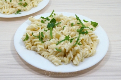 На тарелки выложить макароны в соусе Альфредо. Украсить зеленью петрушки.