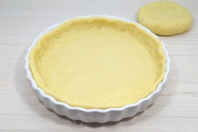 Раскатать большую часть теста тесто в круг. Выложить тестов форму и сформировать бортики.