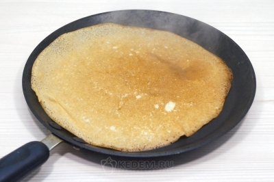 Выпекать тонкие блины с дырочками на сковороде на среднем огне с двух сторон.