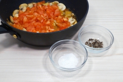 Добавить в сковороду помидоры, 1/4 чайной ложки соли и 1 щепотку черного молотого перца.